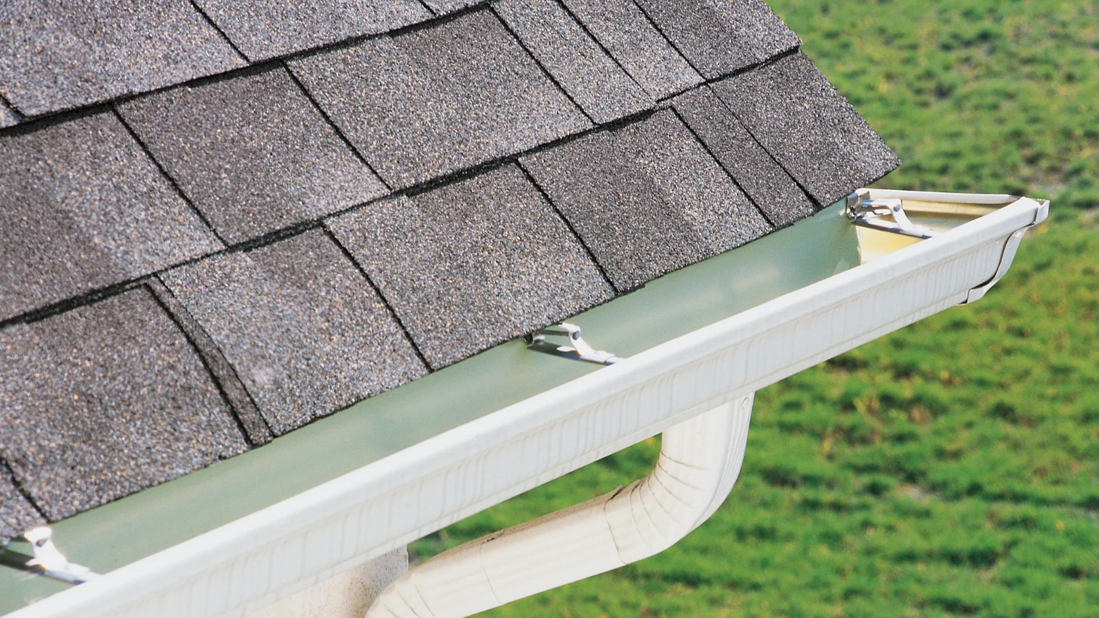 Gutter and downspout at the corner of a shingle roof